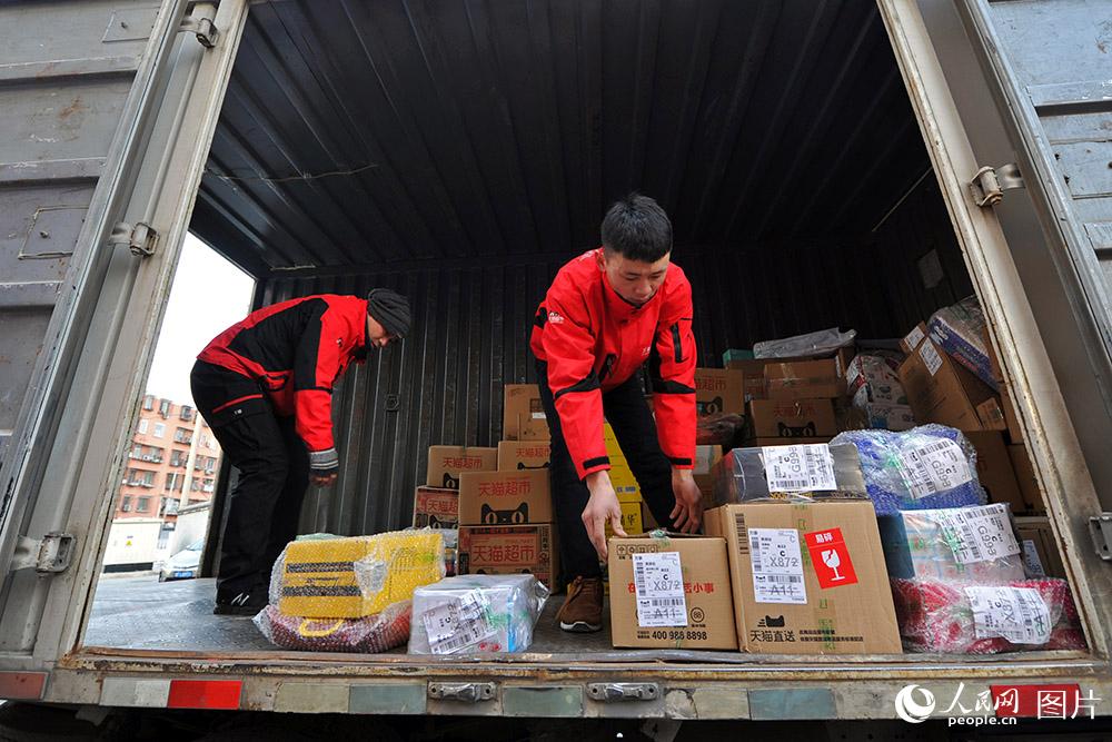  張宏鑫與同事從貨車上卸下當日需要派送的貨物。（人民網記者 翁奇羽 攝）